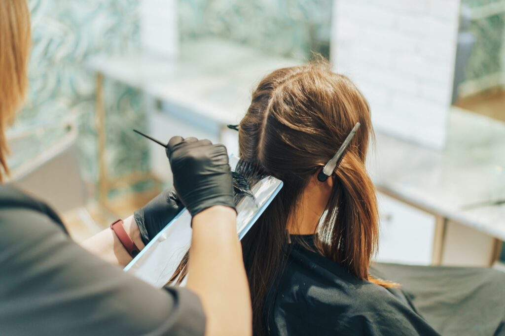hair stylist dyes hair with a brush with foil